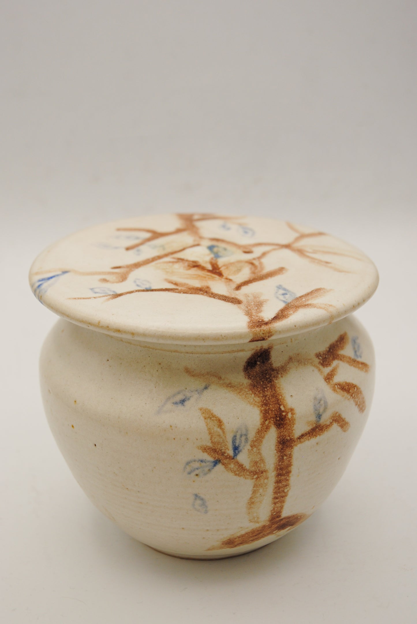 Cream ceramic Tree jar with painted brown branches and blue leaves