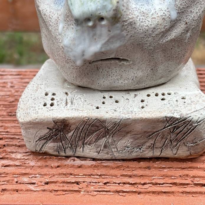 Close up of detailed of Cheri Owen’s ceramic sculpture titled “You Are Safe Totem,” featuring textured glaze and Braille message “You Are Safe”