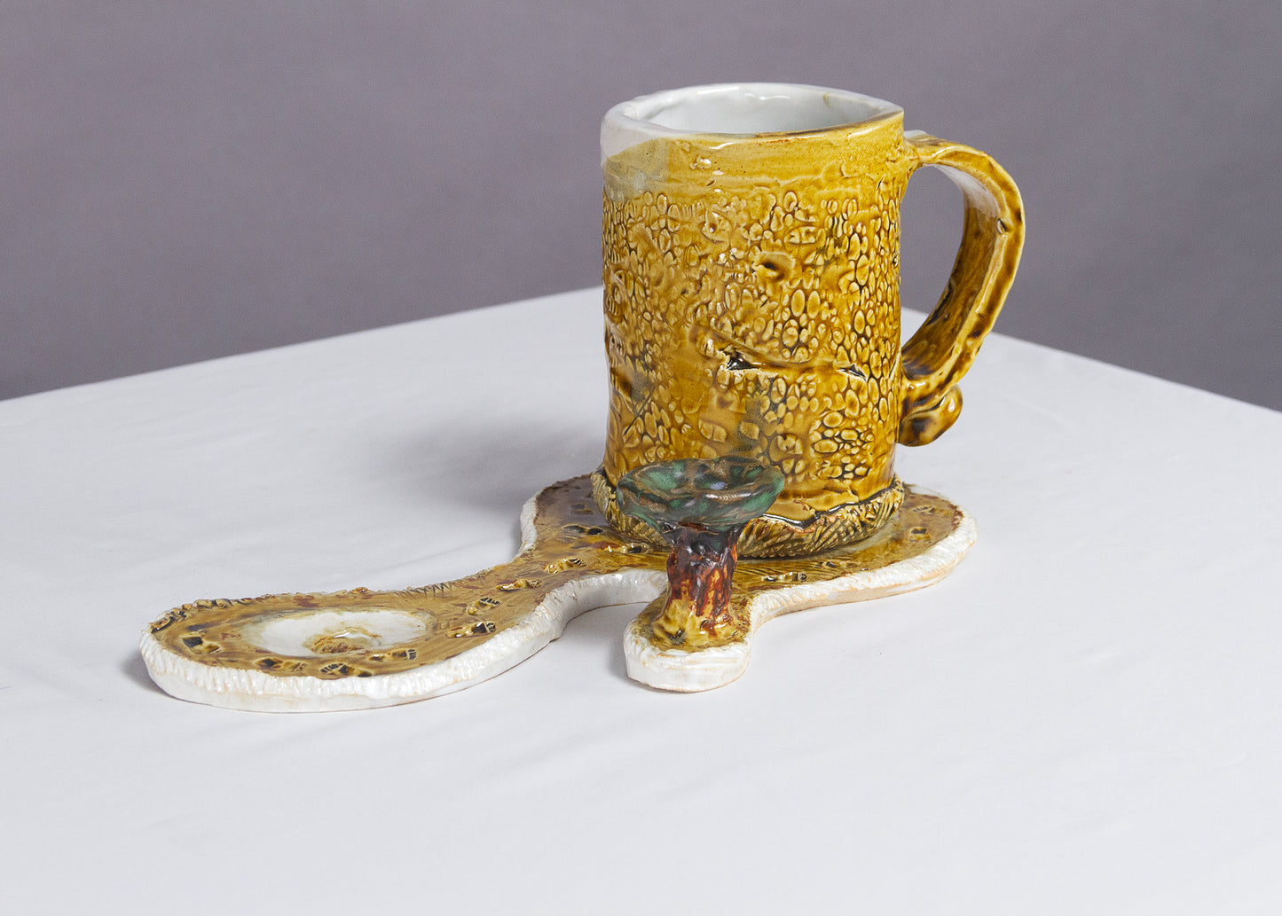 Saucer and Mug textured yellow ceramic set with abstract shapes with a small green tree.