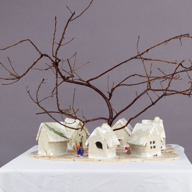 Small white houses under a bare tree branch 