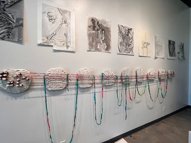 Wall with prints and hand made sculptures called forgive yourself on it.