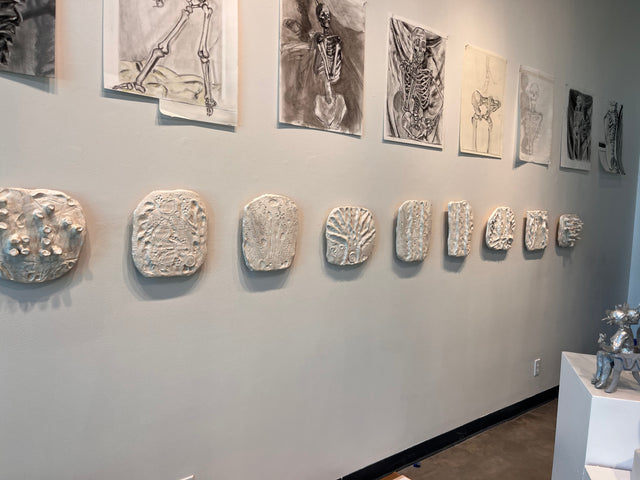 Wall with prints and hand made sculptures on it.