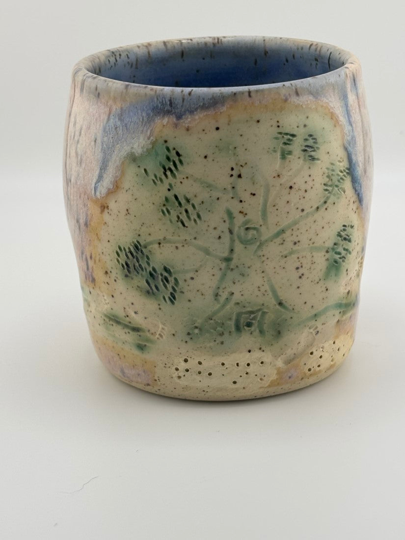 Back of ceramic cup featuring a green-tinted tactile design with Braille text and tree motif.