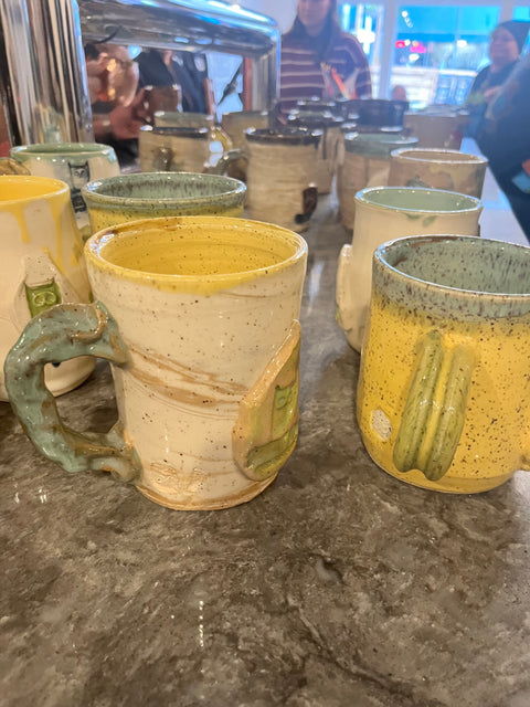 Collection of ceramic mugs with unique designs on a stone surface.