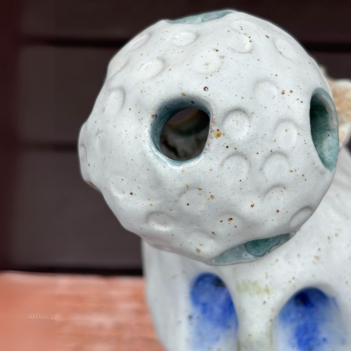 Close up of detailed of the sphere of Cheri Owen’s ceramic sculpture titled “You Are Safe Totem,” featuring textured glaze and Braille message “You Are Safe”