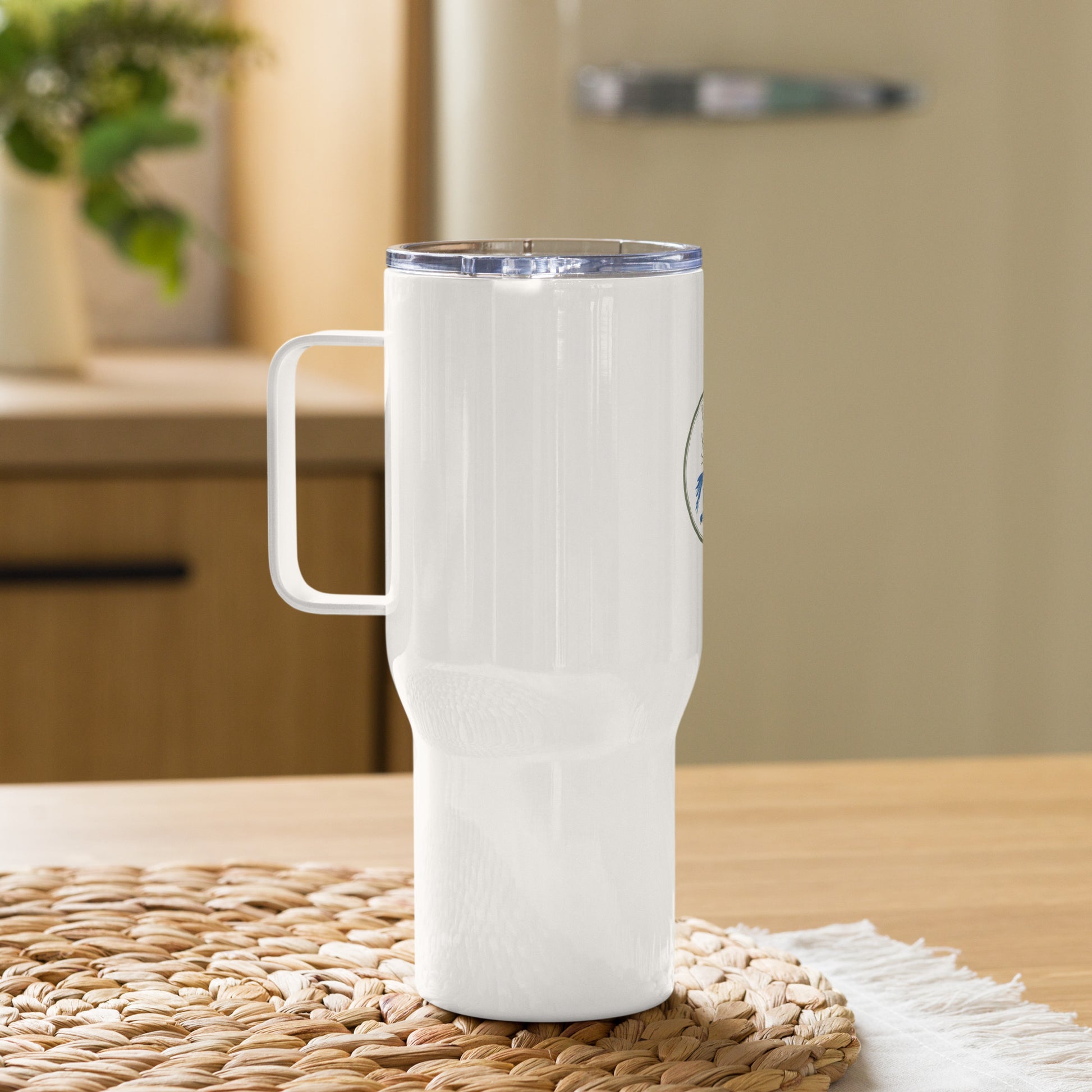 White travel mug with handle on a woven mat in a kitchen setting